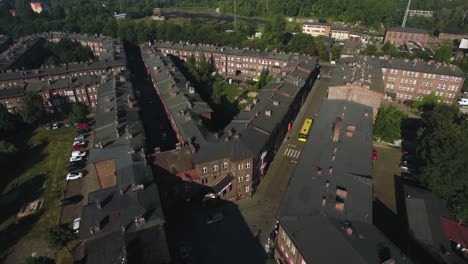 fotografía dinámica de un asentamiento histórico de silesia, con calles, un autobús en movimiento, un bosque y techos con chimeneas, en 4k