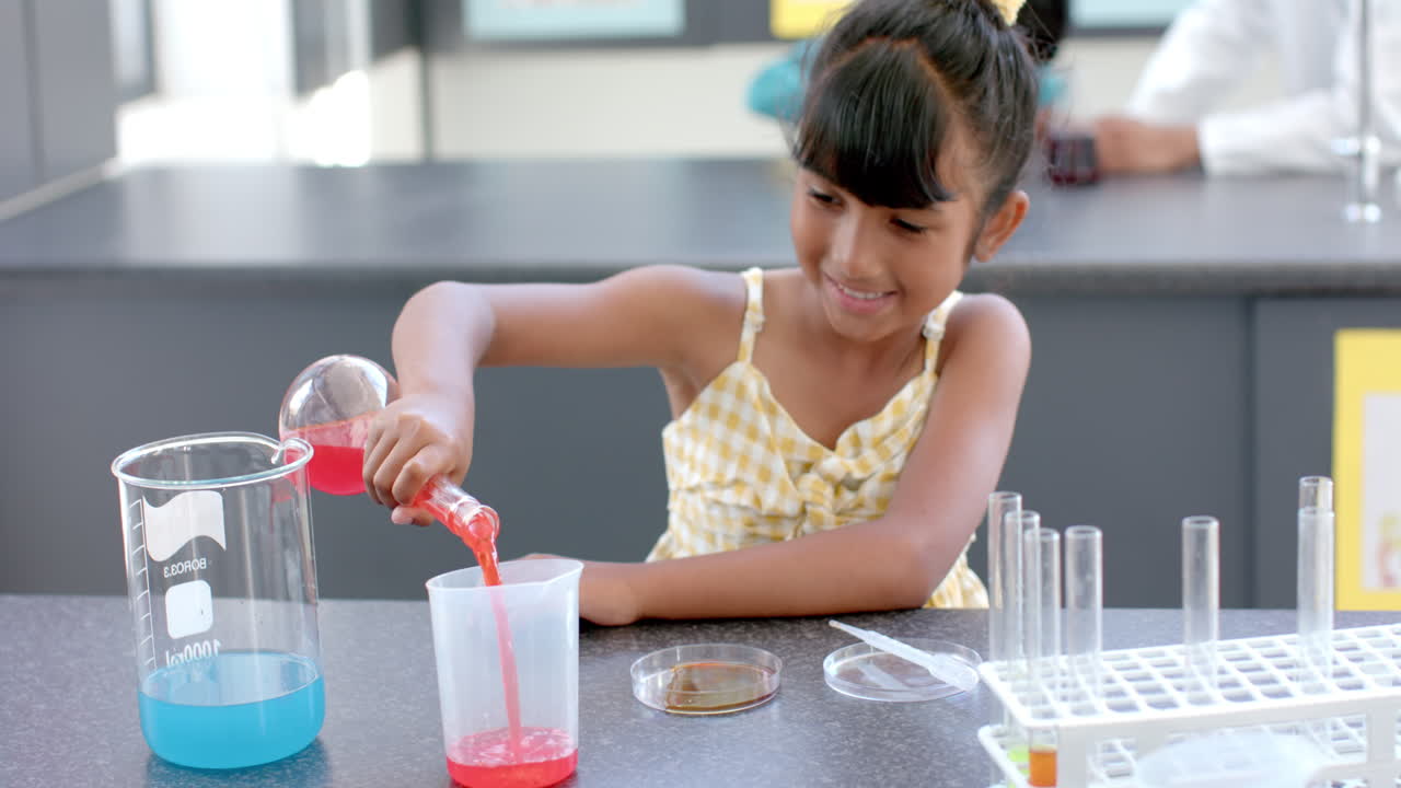 In a school laboratory, a young biracial girl conducts a chemistry experiment