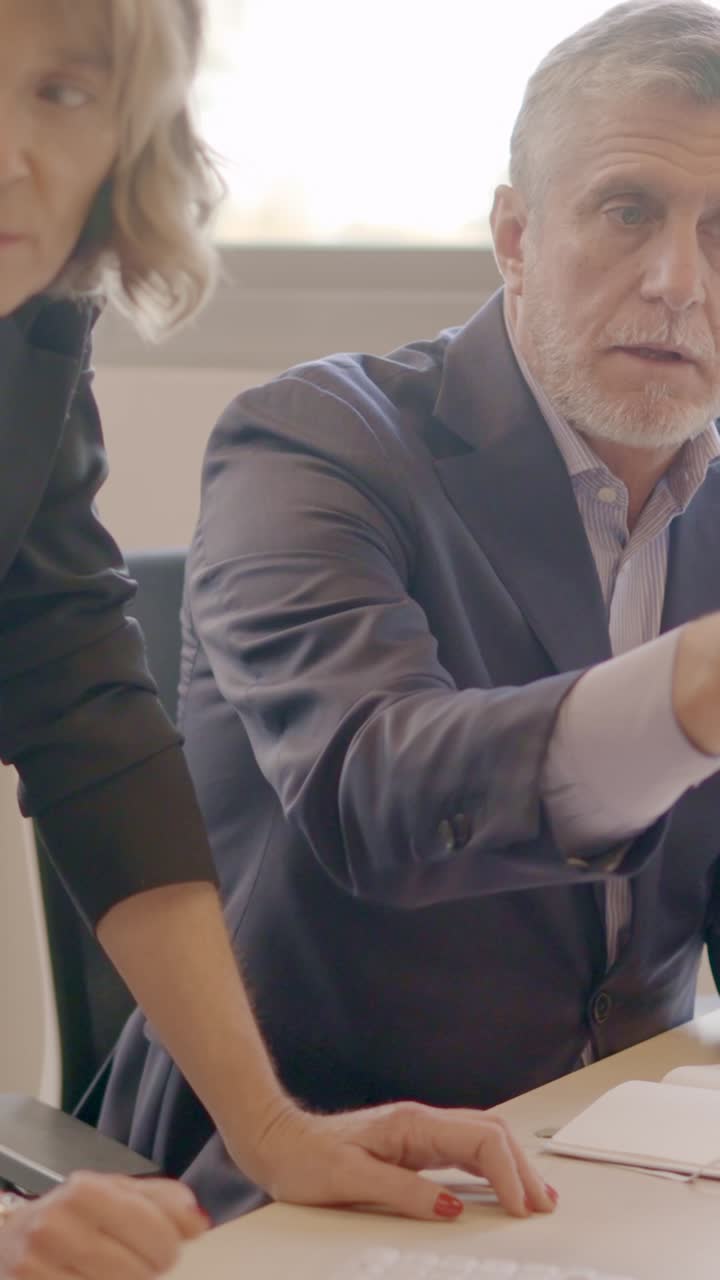 Business partners talking and using computer together in a coworking space