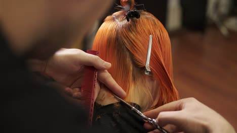 Rückansicht-Einer-Rothaarigen-Frau,-Die-Sich-Im-Schönheitssalon-Von-Einem-Professionellen-Friseur-Die-Haare-Schneiden-Lässt.-Stylist-Friseur-Bei-Der-Arbeit.-Schuss