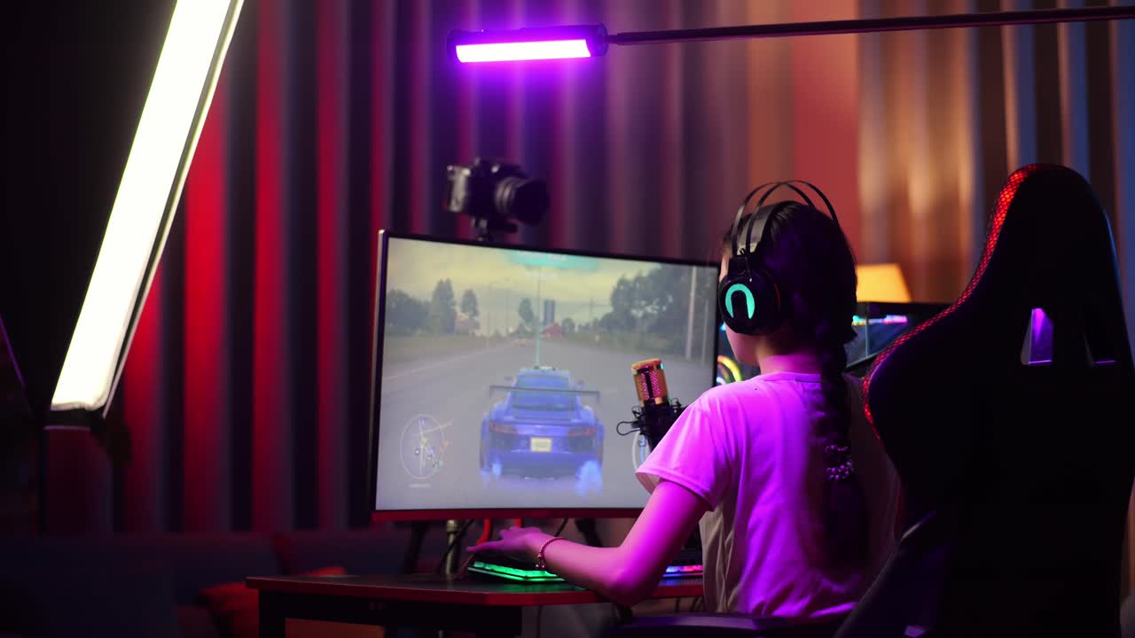 Back View Of Asian Girl Streamer Playing Car Racing Game Over Network On Personal Computer. Yawning And Sleeping, Live Stream Video Game, Desk Illuminated By Rgb Led Strip Light