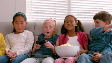 cute little friends sitting on couch together playing video games