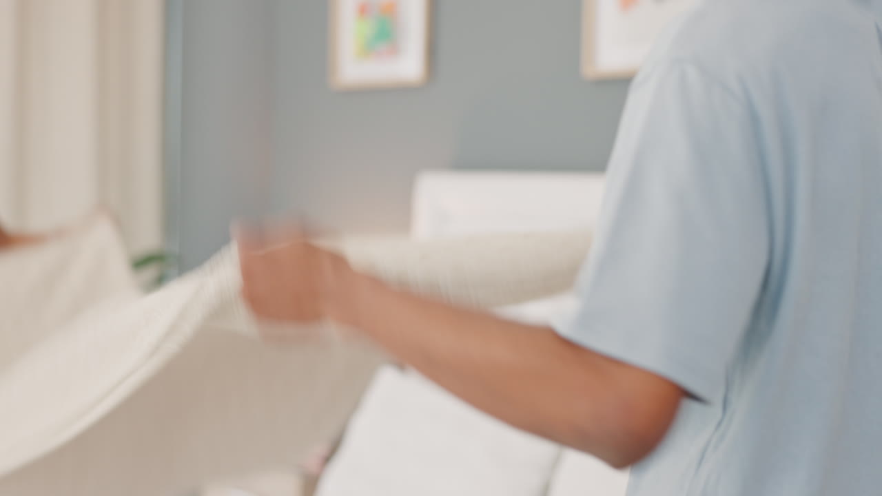 persona que limpia o arregla una manta o alfombra en una habitación