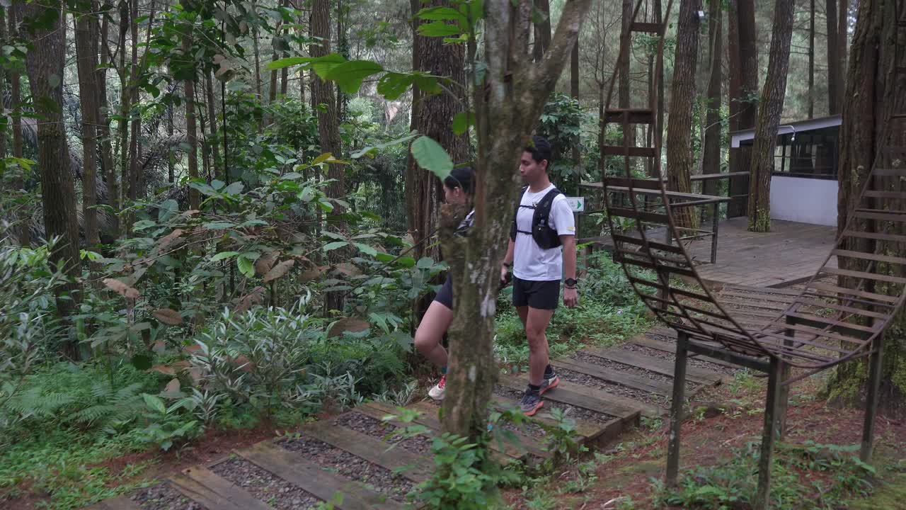 Asian couple walking on forest trail path during outdoor adventure in Indonesia