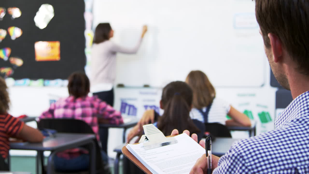 maestro en prácticas tomando notas en una lección de escuela primaria