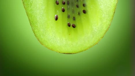 cerca o macro de una rebanada de kiwi, una gota de agua cae en cámara lenta.