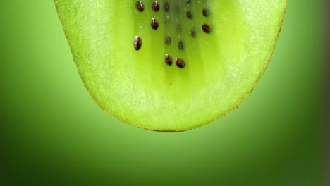 close up or macro of a slice of kiwi, a drop of water falls in slow motion.