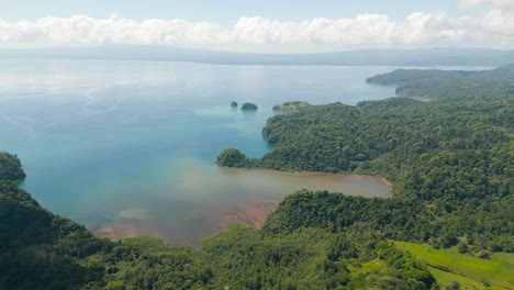 Costa-Rica-beach-drone-top-view-showing-sea,-shore-and-palm-tree-forest-in-Corcovado-National-Park-on-a-sunny-day-in-the-pacific-ocean