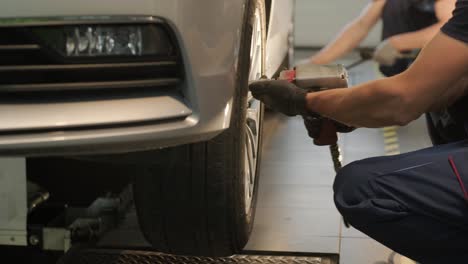 mecánico de automóviles reemplazando un neumático de automóvil en un taller de garaje. cámara lenta. servicio de automóviles