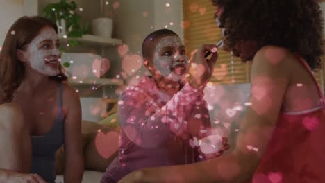 animation of hearts over diverse group of female friends with beauty face masks