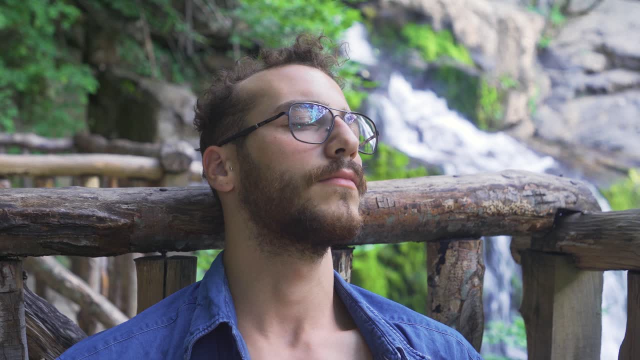 el hombre está durmiendo y descansando en el borde de la cascada que fluye en el bosque.