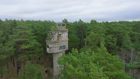 establecimiento de una vista aérea de la antigua torre de vigilancia de observación de hormigón militar soviética, bosque de pinos, liepaja, patrimonio militar, bosque nórdico, amplio tiro descendente de drones