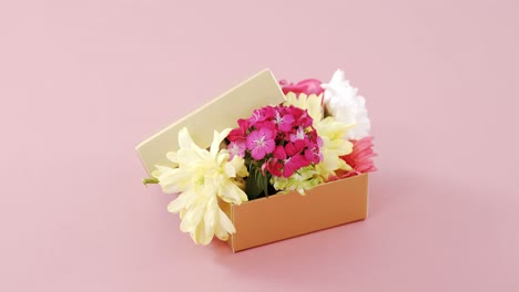 Caja-De-Regalo-Llena-De-Flores-Sobre-Fondo-Rosa