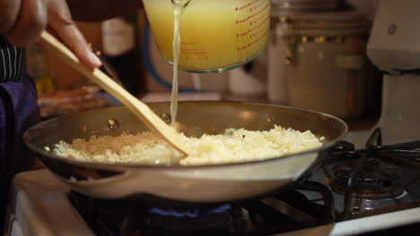 pouring chicken broth over rice and stirring in the steaming homemade stock - slow motion