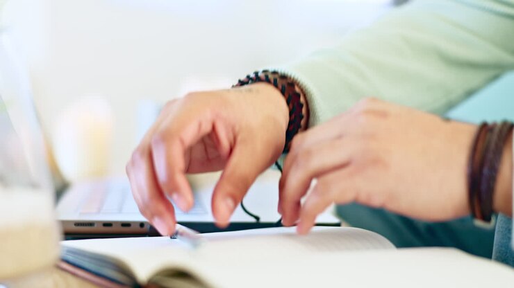 Mani che digitano, laptop e scrittura su libro