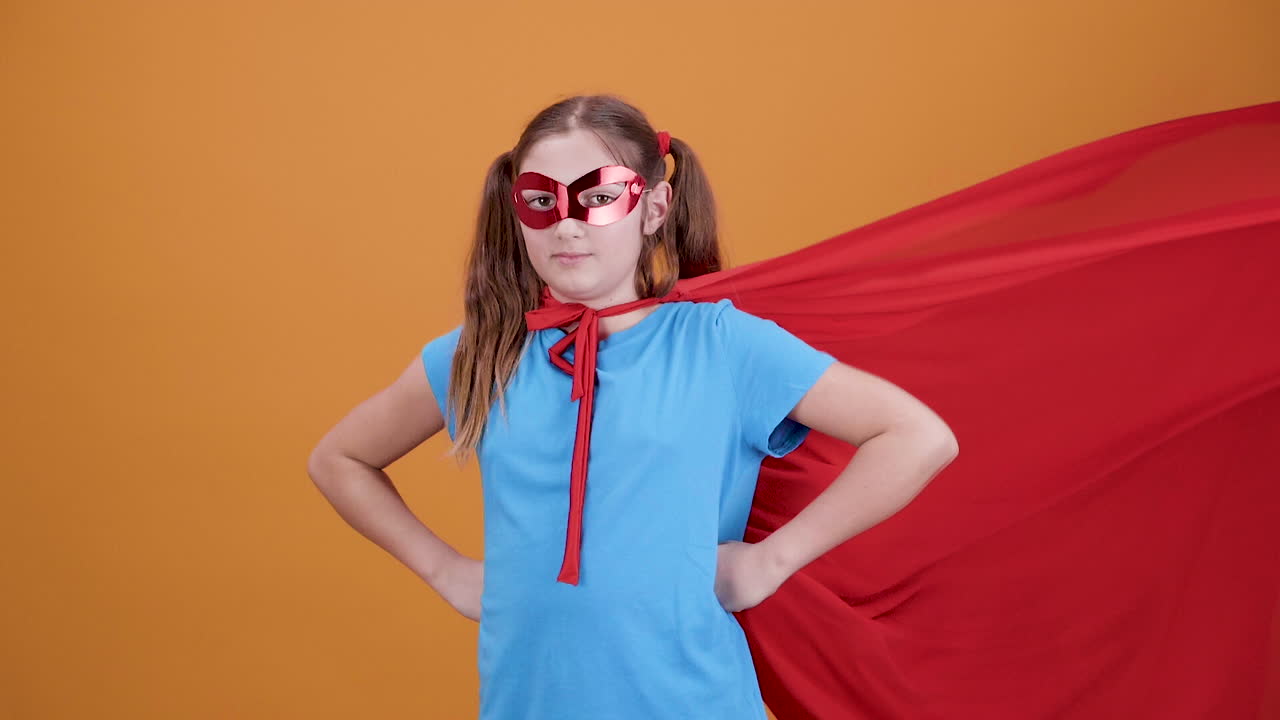 Girl in superhero costume with cape and mask