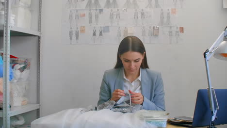 a young girl designer sewing a dress in the studio dress. making clothes sewing beads and jewelry. seamstress decorates a dress in the studio.