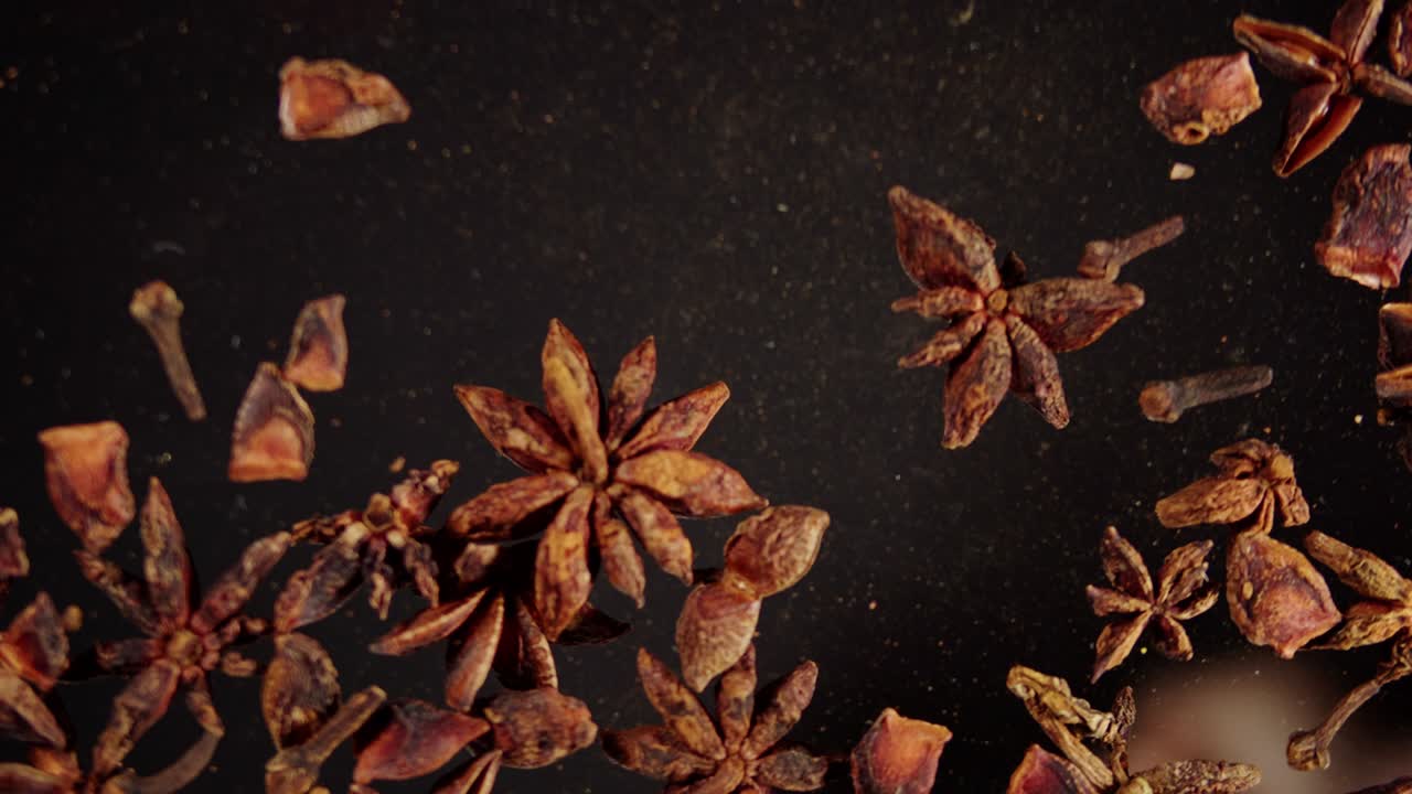 verter anís estrella en vidrio sobre fondo negro de primer plano. cultura de oriente medio y árabe. condimentos y sabores. hierbas secas para cocinar.