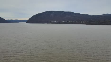 aerial-footage-of-a-wide-river-valley-with-distant-mountains-covered-in-a-dusting-of-snow-during-winter