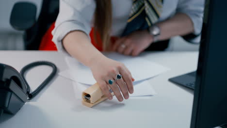 Close-up-of-secretary's-Hand-using-yellow-office-stapler-to-bind-two-papers-together