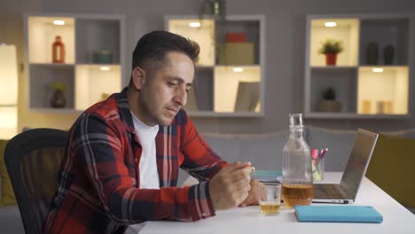 thoughtful man with wedding ring in hand drinking alcohol.