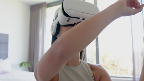 una adolescente caucásica de cabello castaño está inmersa en la realidad virtual, usando un auricular vr en casa
