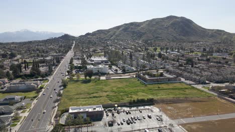 in a slow pull-out, this drone footage reveals a tapestry of commercial and residential buildings in riverside, california, all set against the majestic backdrop of blue mountain