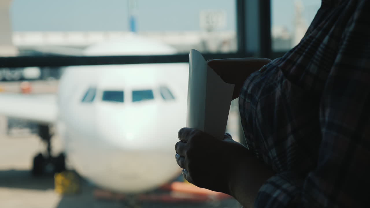 비행기를 기다리는 동안 공항 터미널 창가에서 간식을 먹고 있는 여성의 실루엣