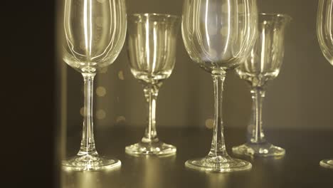 close-up view of several empty crystal glasses on wooden table, reflected christmas lights