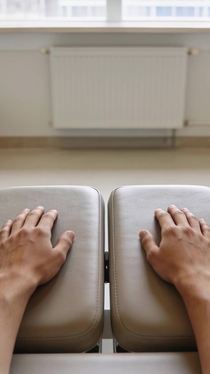 Vertikal video: Hænder placeres på delte puder i et klinikrum, der viser bare underarme.