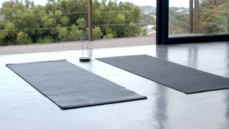 yoga mats on floor with incense burning, creating peaceful home workout space, copy space