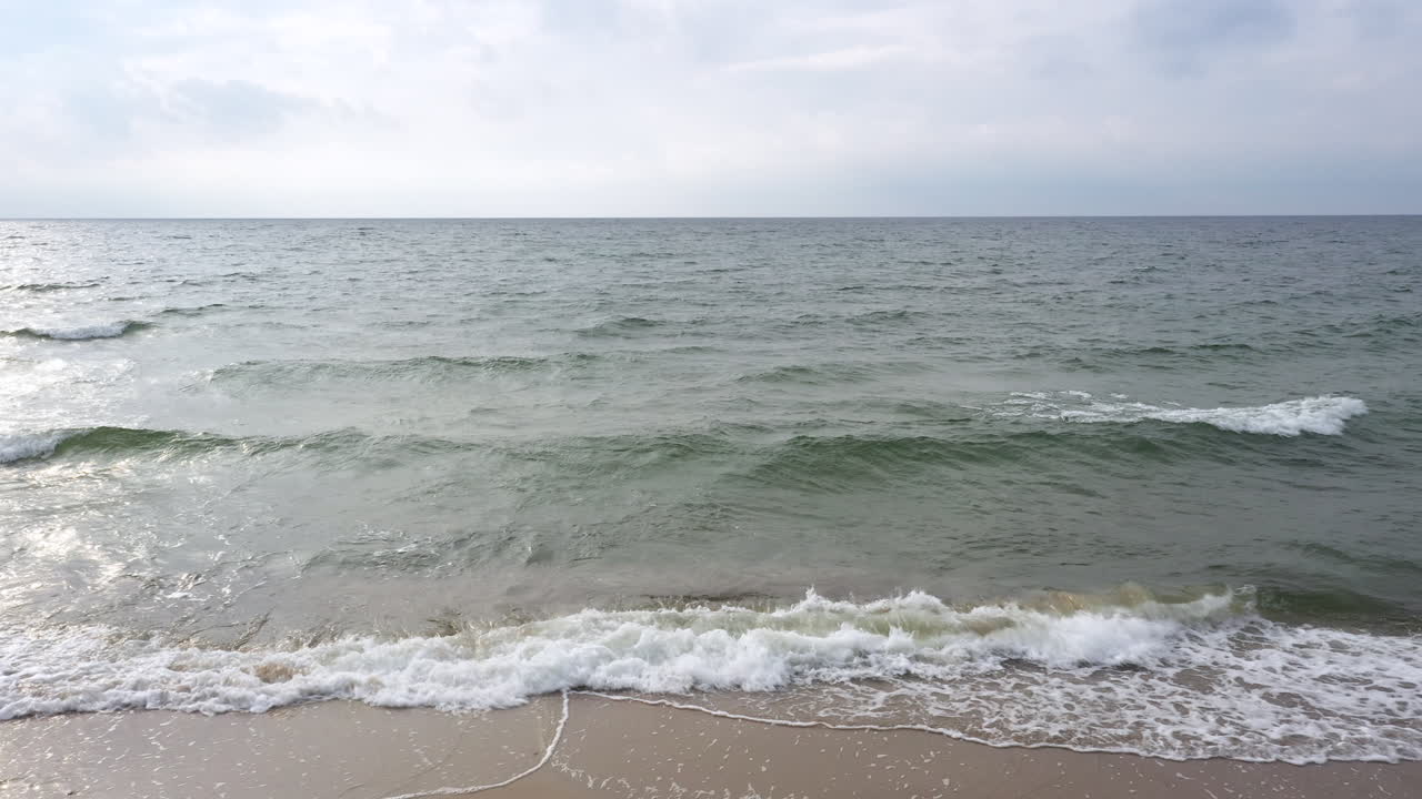 공중: 어두운 파동하는 바다 위의 해변의 잠금 과 배경에 구름이 인 하늘