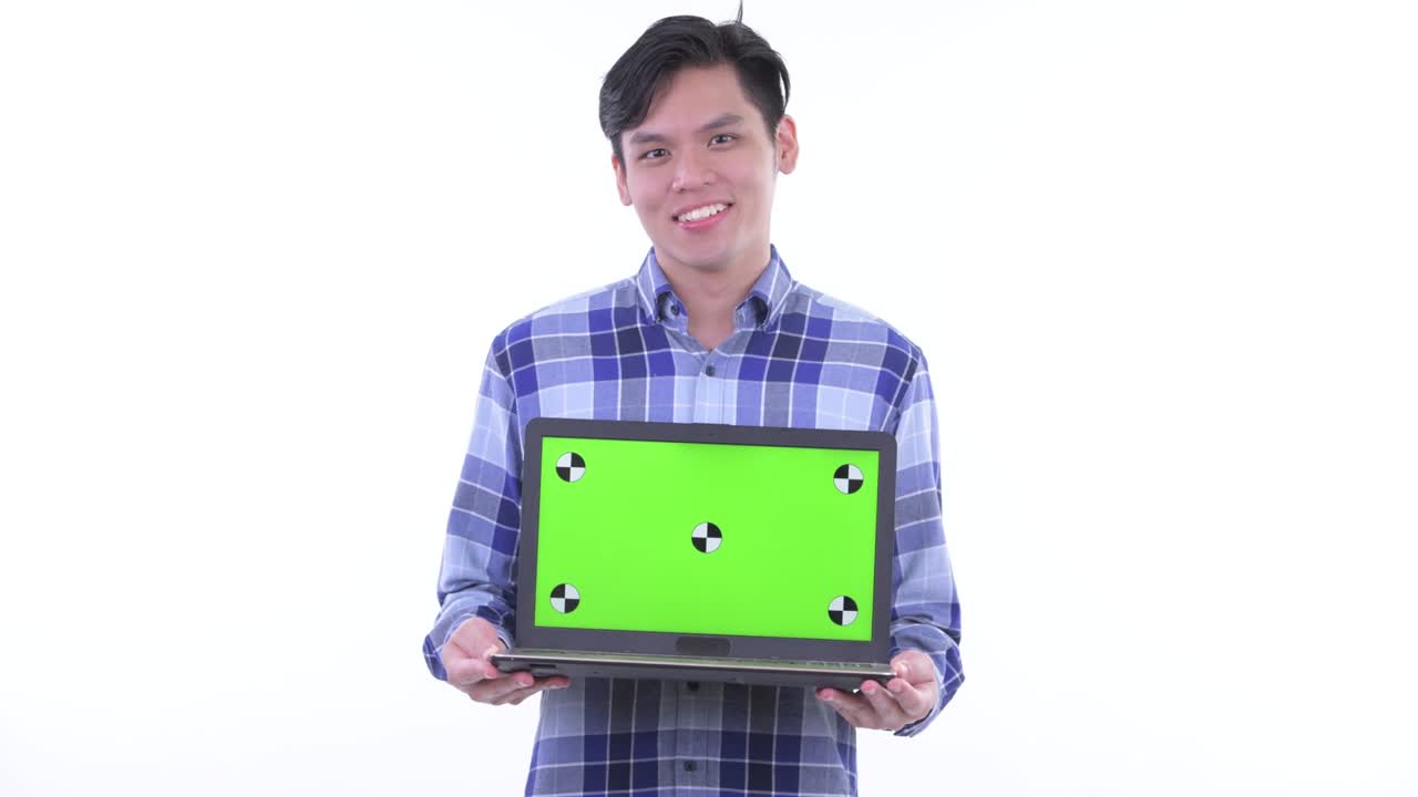 젊은 잘생긴 아시아 남자의 초상화 색 배경에 고립 된 복사 공간으로 노트북을 들고 생각하고 미소 짓고 있습니다.