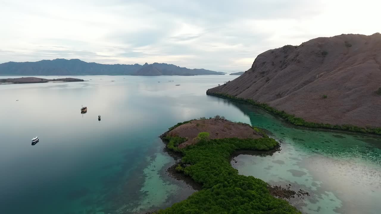 vista aérea de barcos en la costa del parque nacional de komodo, labuan bajo, indonesia - marcha atrás, disparo de drones