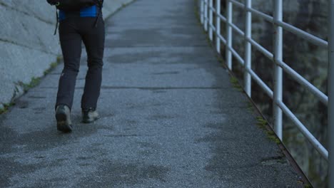 Hiker-walking-along-a-concrete-slope-and-a-metal-railing