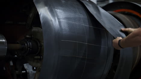 tyre factory worker hands setting new rubber tape on industrial workshop machine