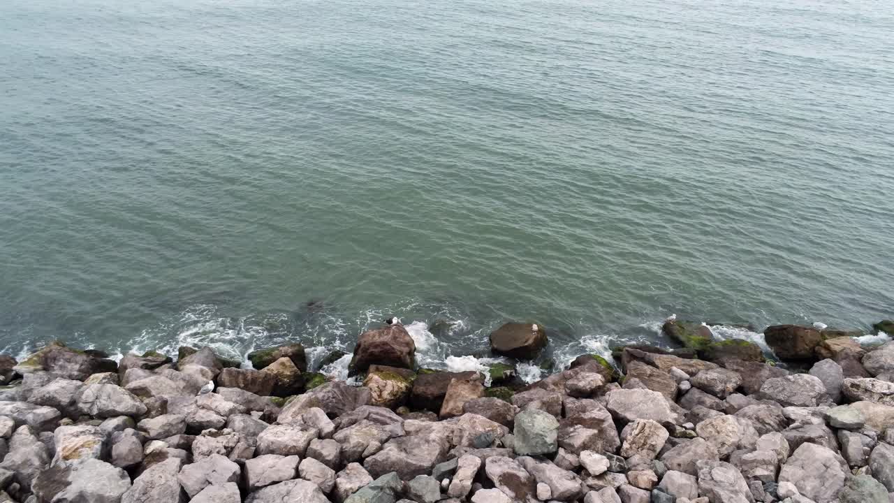 바위가 많은 해안선 느린 팬 왼쪽에 부서지는 튀는 바다 조수 위의 조감도