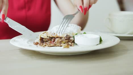 unrecognizable girl in red dress taking desert strudel at the restaurant using fork and knife. slow motion shot