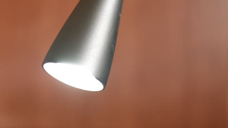 Close-up-modern-desk-lamp-lightbulb-turning-on-increasing-three-levels-of-brightness