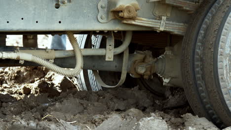 a truck stuck deep in the mud is trying to move up and out of the muck by accelerating and gaining momentum, in a ricefiled outside of bangkok, thailand