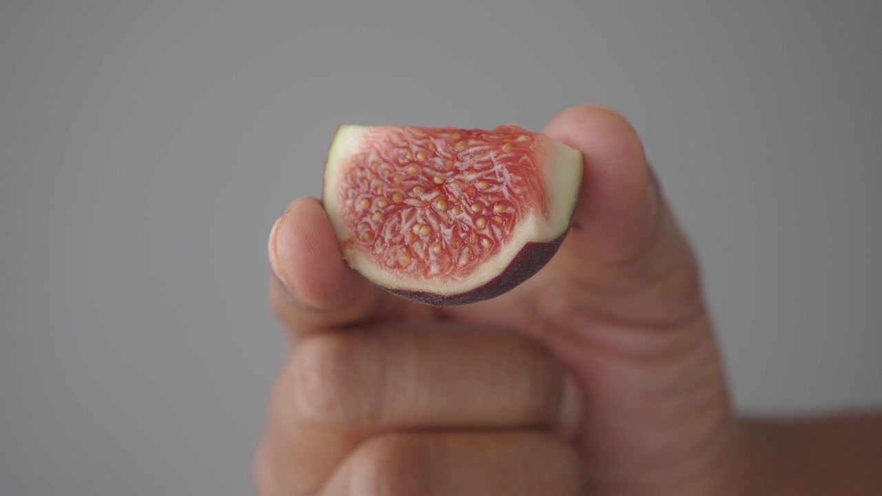 Hand Holding a Fresh Slice of Ripe Fig