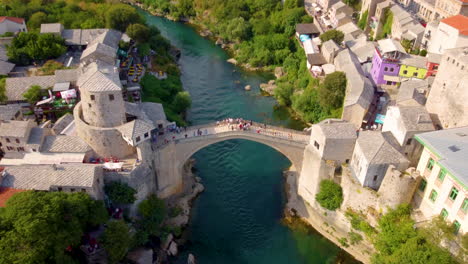 locals and tourists crossing at famous stari most over neretva river in mostar, bosnia and herzegovina