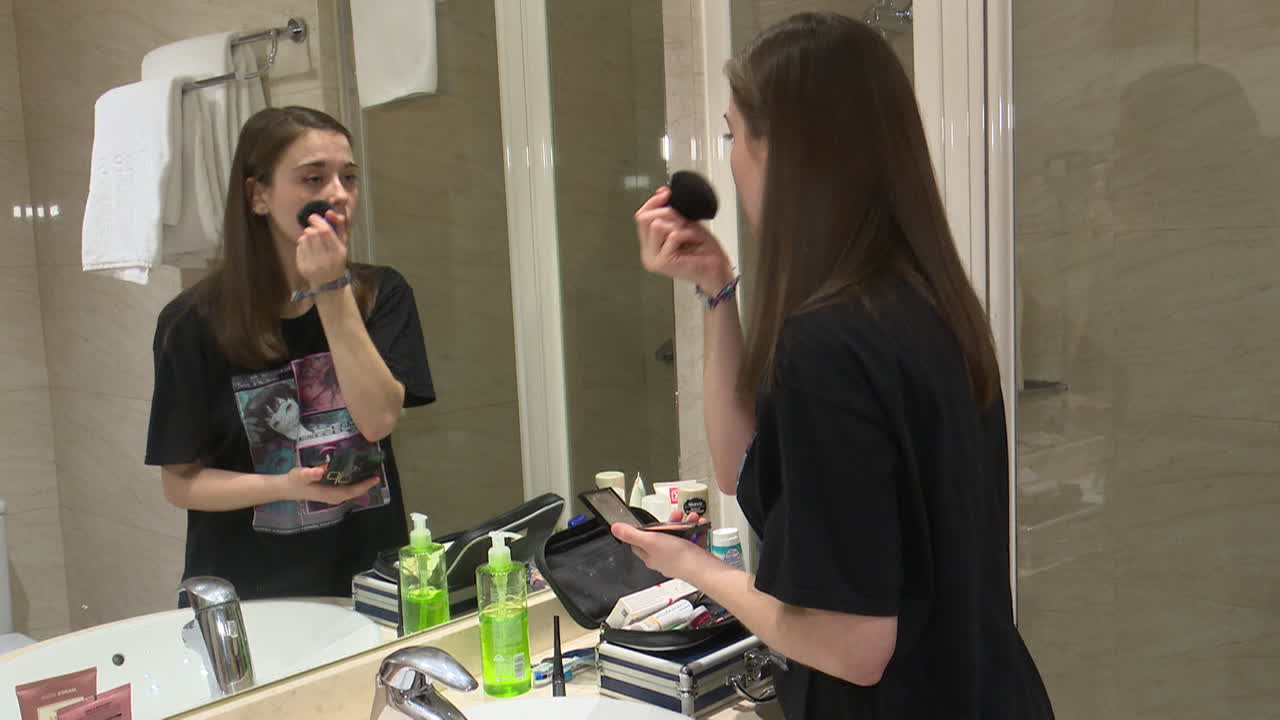 Teenage Girl Applying Makeup in Bathroom