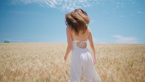 beaming lady walking sunny wheat farmland. happy girl spinning summer nature