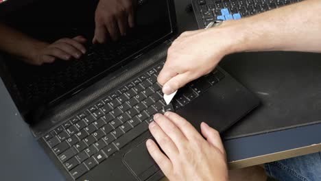 repair of an old laptop, the technician uses a knife to remove keys from the keyboard