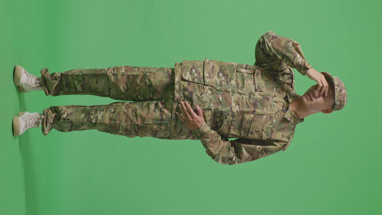 Full Body Of Asian Man Soldier Having A Headache While Standing In The Green Screen Background Studio