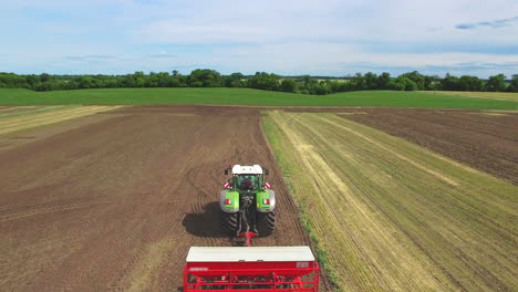 agricultural tractor with trailer plowing agricultural field. farming aerial