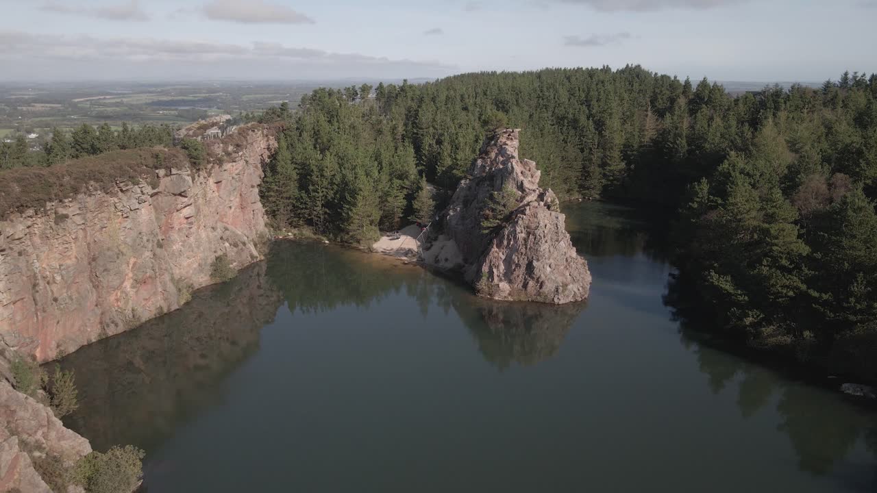 vista pintoresca del lago de la cantera de carrigfoyle con peñascos y bosques de coníferas en barntown, condado de wexford, irlanda