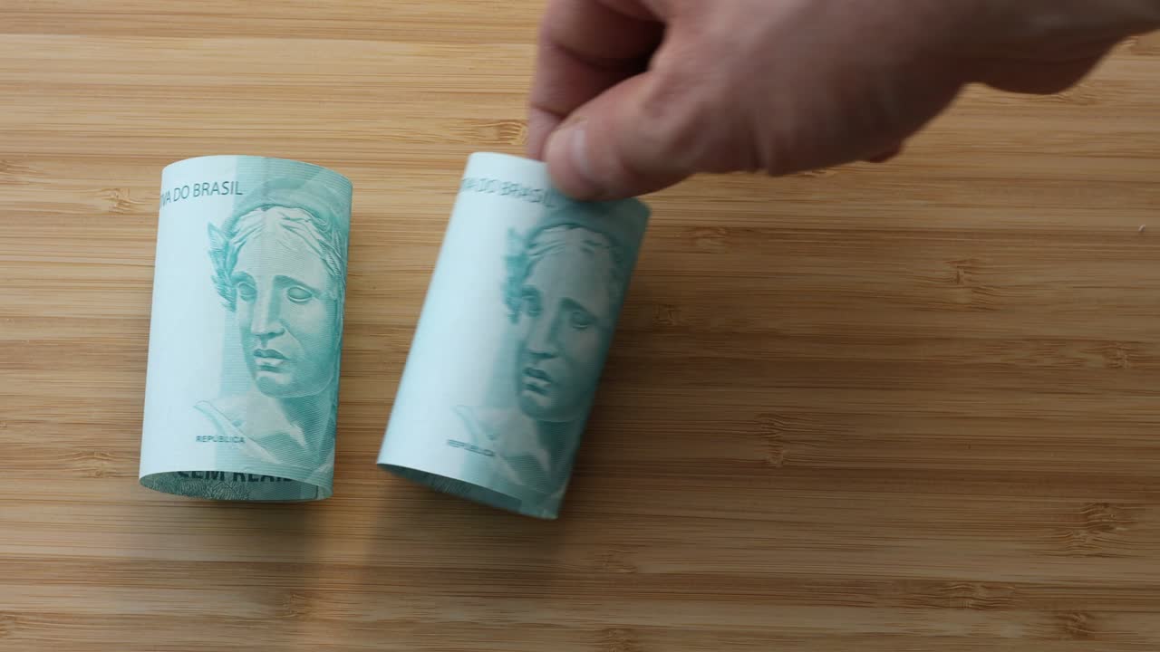 dinero brasileño, enrollado y puesto sobre la mesa, billetes de gran valor, 100 reales cada uno