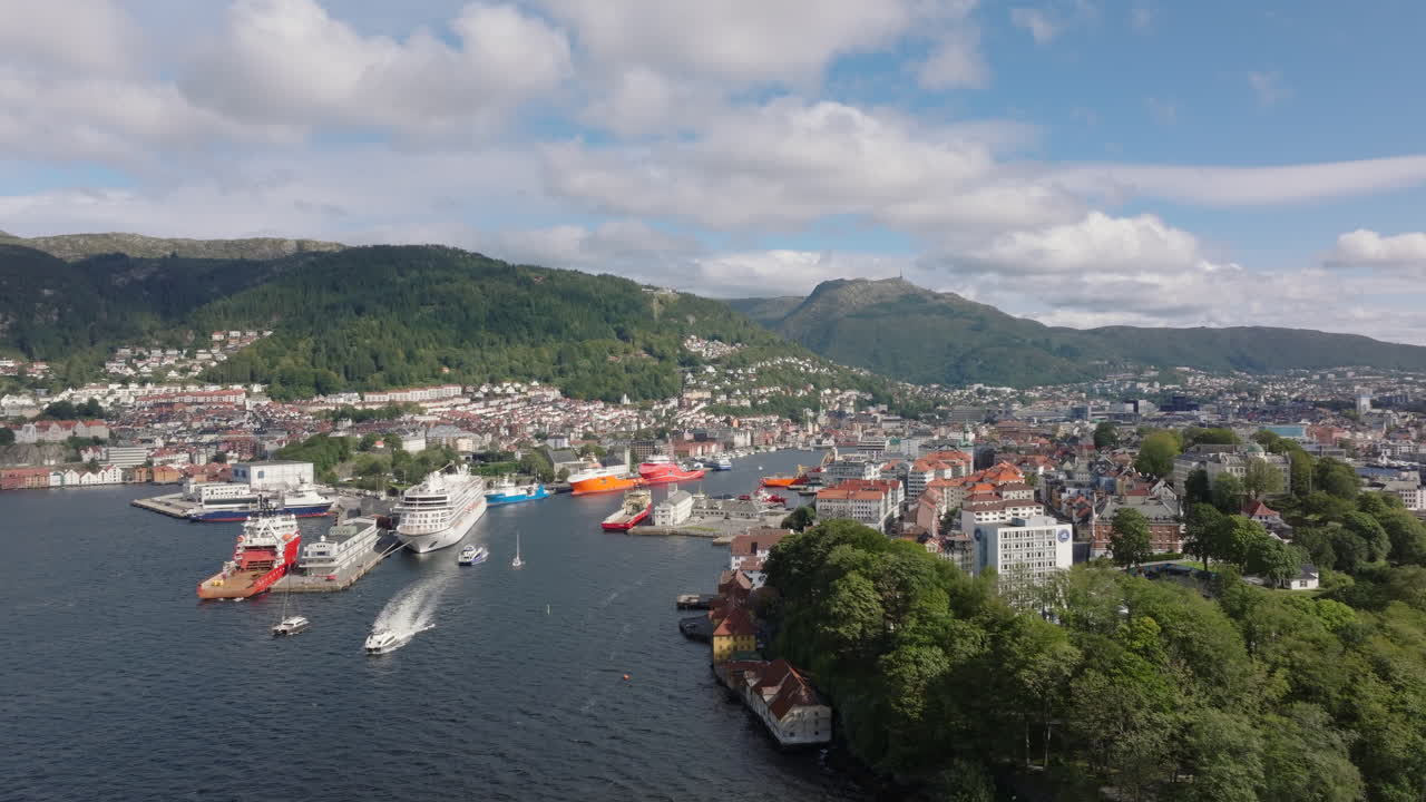 Drone shot gliding laterally along Bergen’s coastline, with fjords and mountains in view